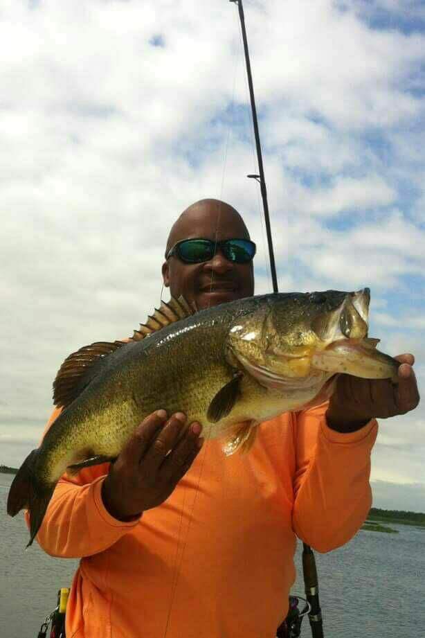 Angler in orange shirt with a trophy bass on Lake Toho