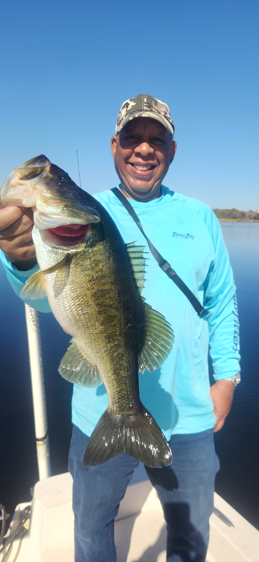 Smiling angler in light blue holding a big bass